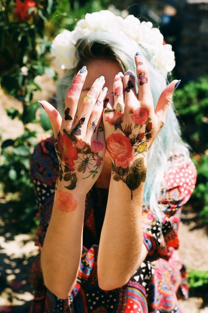 Blumen Tattoos an beiden Händen, farbige Tattoos, blauer Nagellack, buntes Sommerkleid, weißer Blumenkranz