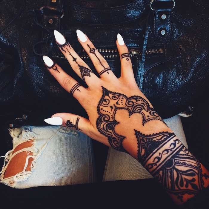 Schwarzes Henna Tattoo an der Hand, weißer Nagellack, spitze Nägel