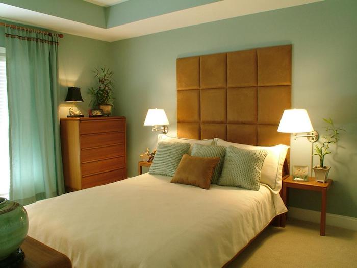 zwei weiße lampen in einem schlafzimmer mit einem bett mit einer weißen decke und braunen und grünen kissen, ein fenster mit einem grünen vorhang, blumentöpfe mit grünen pflanzen und grünen blättern