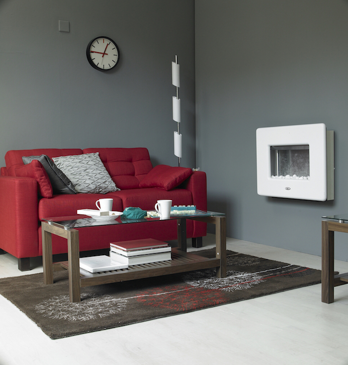 eine graue wand mit einer schwarzen wanduhr, ein wohnzimmer mit einem roten sofa und einem kleinen braunen tisch, gemütliche wohnzimmer farben