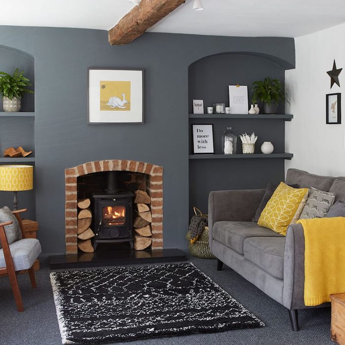 wohnzimmer grau weiß, kamin, regale mit dekorationen, graues sofa mit gelben dekokissen