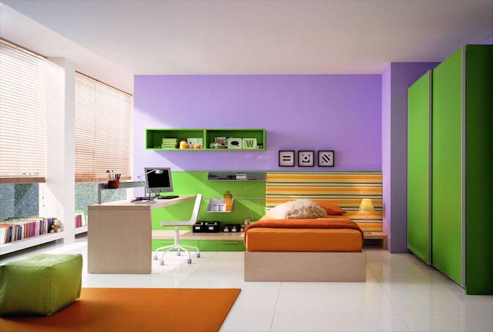 eine große violette wand mit drei bildern und grünen regalen, ein oranges bett und ein schreibtisch aus holz und ein stuhl, kinderzimmer einrichten, wandfarbe schlafzimmer