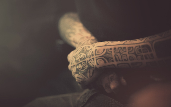 zwei hände mit vielen schwarzen polynesischen tätowierungen, symbole für stärke kraft mut, maori tattoos für männer 
