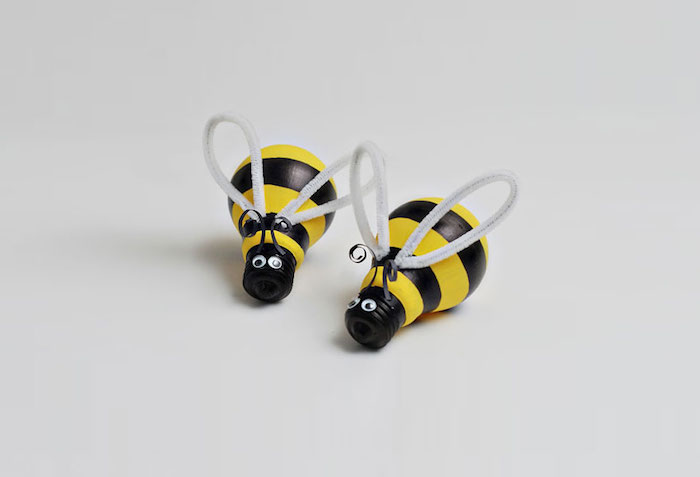 zwei kleine gelbe bienen mit schwarzen augen und mit grauen flügeln und aus zwei bemalten alten glühbirnen