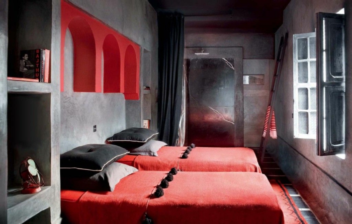zwei Betten mit roten Decken, schwarze Kissen, Schlafzimmer in grauer Farbe
