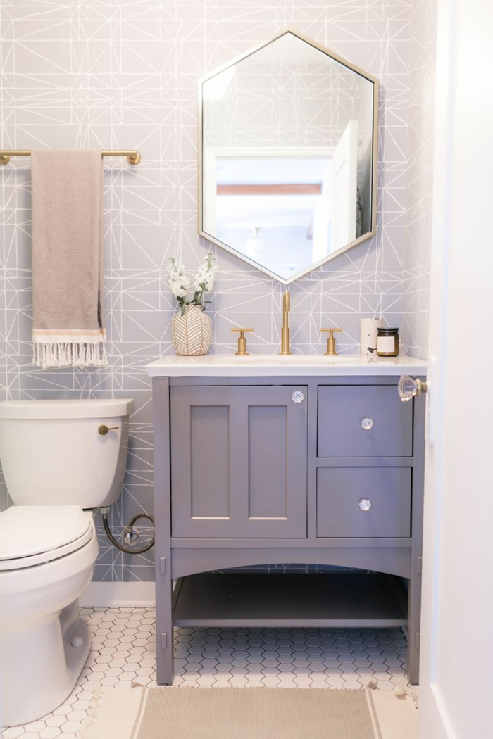 ein schöner Spiegel, blaues Bademöbel Set, ein kleiner beiger Teppich, weiße Mosaikfliesen, kleines Bad gestalten