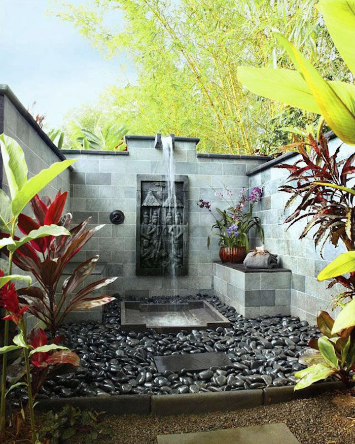 gartengestaltung ideen, ein garten mit vielen grünen pflanzen und einer dusche, sichtschutz für gartendusche, gartenweg aus schwarzen und grauen steinen