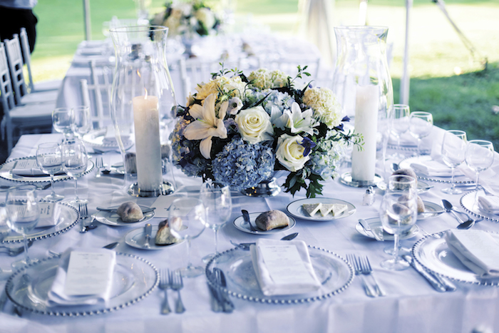 deko hcohzeit in blau und weiß, hohe kerzen, kerzenhalter aus glas, rosen, hortensien und lilien