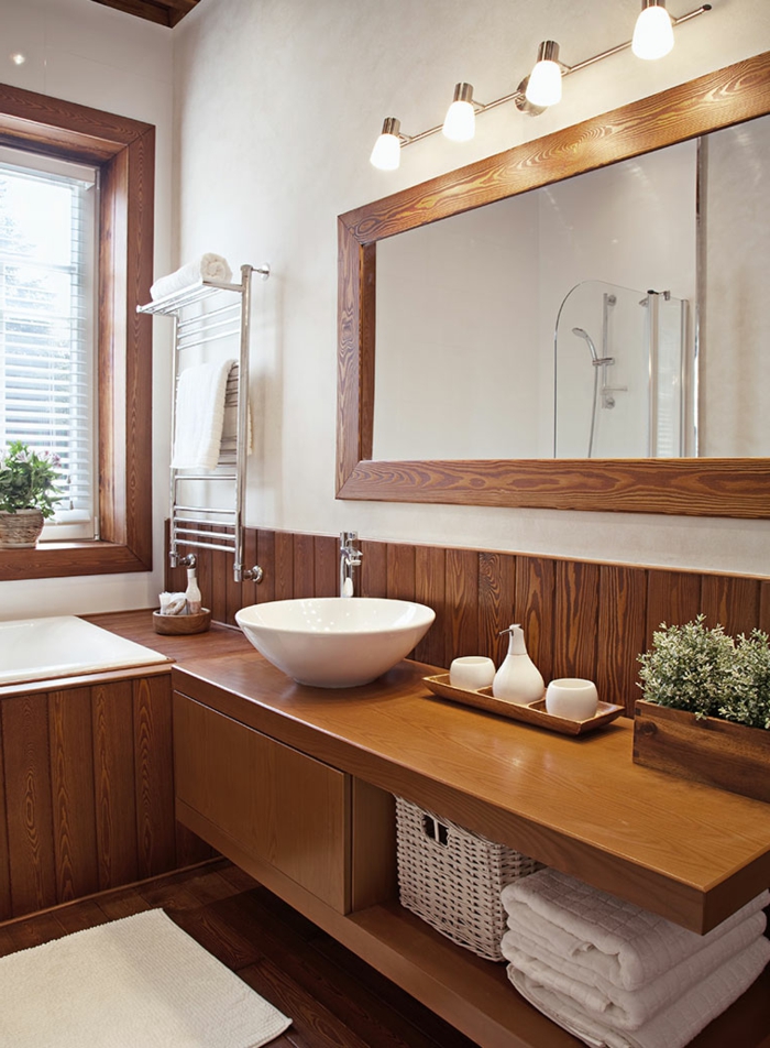 ein großer Spiegel mit indirekter Beleuchtung, ein rundes Waschbecken, schöne Badezimmer aus Holz