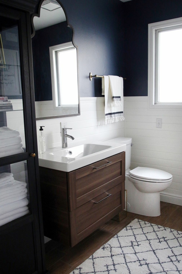 blaue Wände oben, Fliesen unten, Badezimmer Gestaltungsideen, kleiner weißer Teppich, Badmöbel Set aus Holz