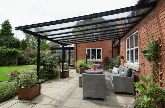 garten mit grauen möbeln aus rattan und ein haus mit einer schwarzen terrassenüberdachung