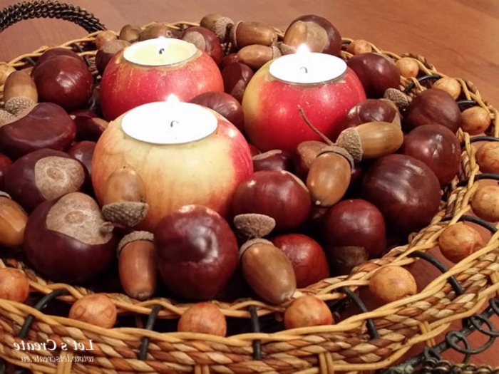 Kastanien Deko, ein Korb mit drei Äpfel, auf denen Teelichter stehen, Kastanien und Eichel