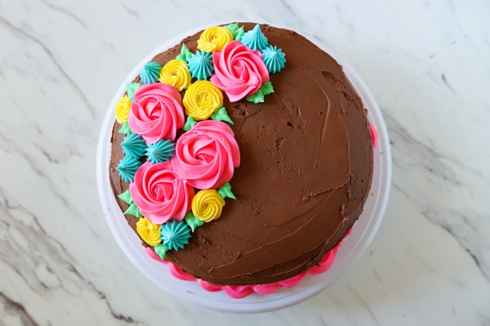 eine bunte Torte mit farbenfrohen Blumen, rosa Creme, Kuchen backen zum Geburtstag