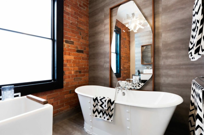 Badezimmer Gestaltungsideen, eine weiße Badewanne mit schwarz weißen Badeücher, Backstein Wand