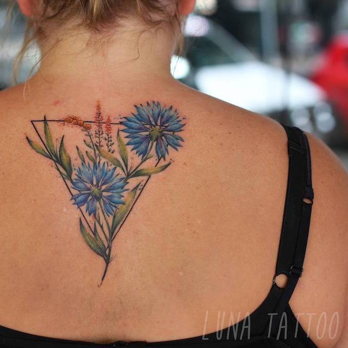 geometrische frauen tattoos, eine frau mit einem rücken mit einem großen watercolor tattoo mit einem dreieck und mit blauen blumen und grünen blättern