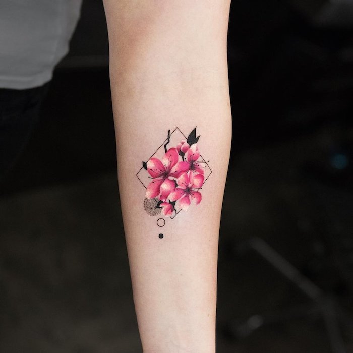frauen tattoos motive, eine hand mit einem kleinen tattoo aquarell mit kleinen pinken blumen und schwarzen blättern und geometrischen formen, watercolor painting