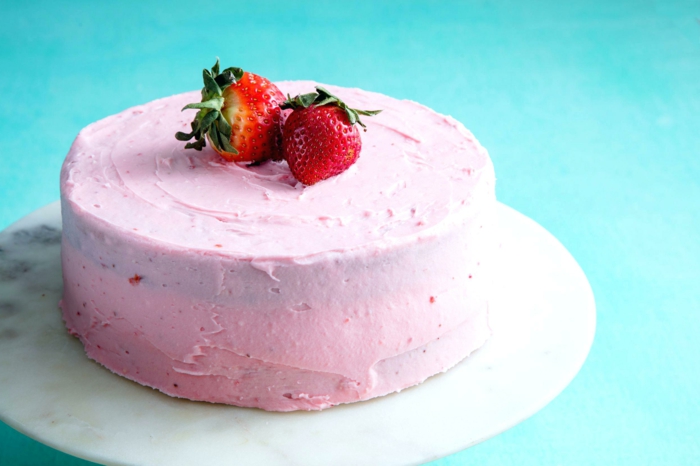 eine rosa Torte mit kleinen Erdbeeren als Dekoration auf blauer Hintergrund, schneller Kuchen 