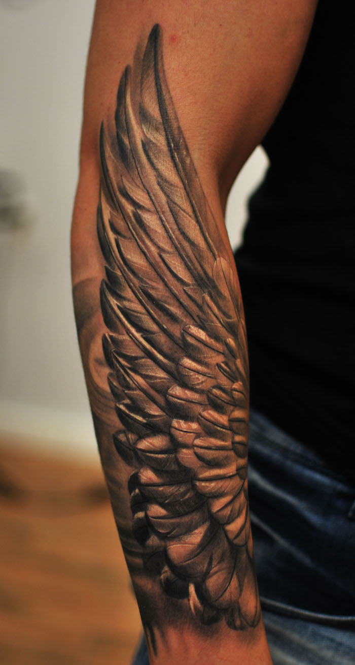 engelsflügel tattoo arm, mann mit realitischer 3d tärowierung am unterarm