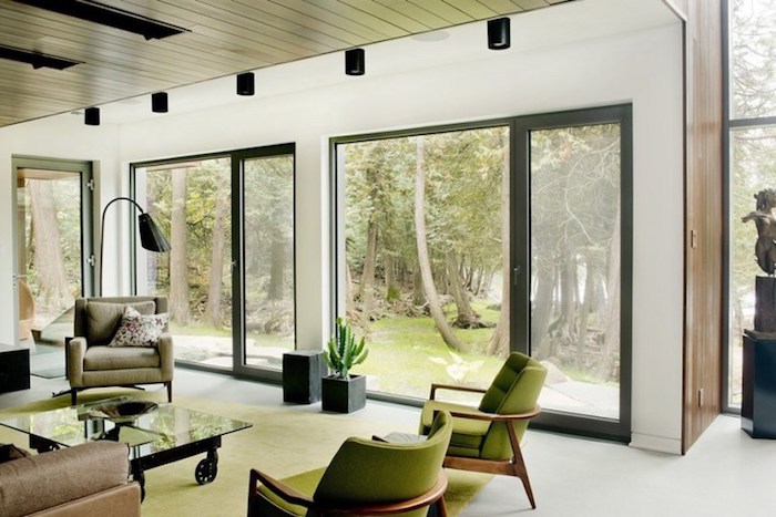 wandgestaltung wohnzimmer, naturnahes interieur, grüne sessel, fenster, wand aus glas