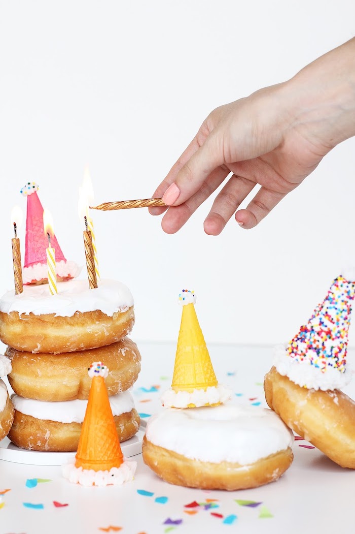 Donuts mit weißer Glasur anstatt Geburtstagstorte, kleine Waffeln mit Zuckerstreuseln, goldene Kerzen