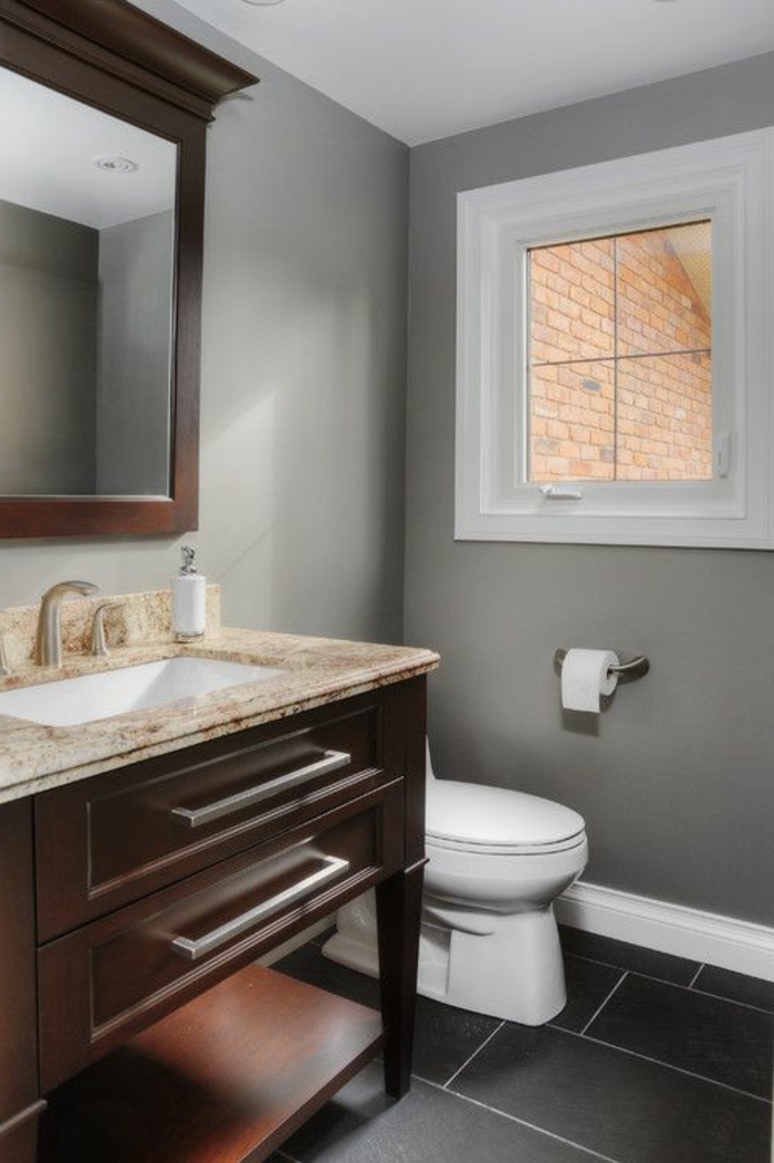eine graue Wand, schwarzer Boden, ein Waschbecken mit braunen Unterschränken, günstige Badmöbel für kleine Bäder