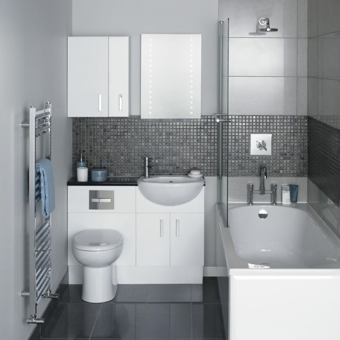 grauer Fliesenboden, graue Mosaikfliesen an den Wänden, Minibad, eine schöne weiße Badewanne, Spiegelschrank mit LED Beleuchtung