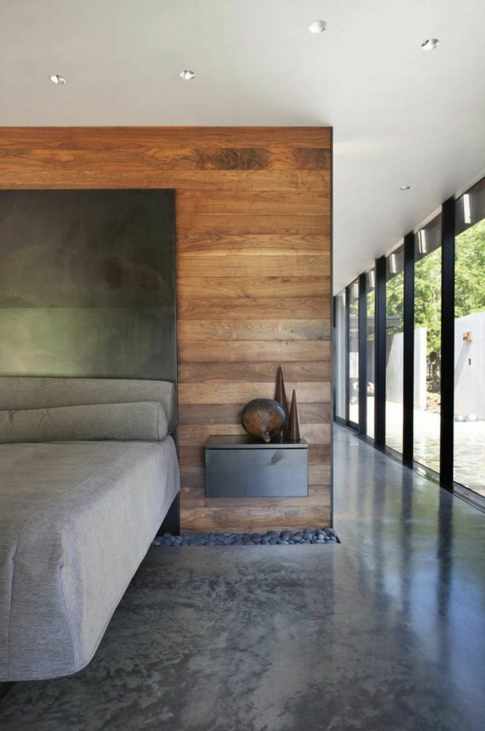 ein graues Bett, grauer Nachttisch, Betonboden Wohnbereich, Kies Dekoration, Betonboden Wohnbereich