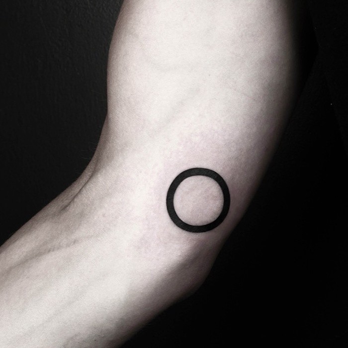 eine hand mit einem kleinen schwarzen geometrischen tattoo mit einem schwarzen kreis, symbol für stärke
