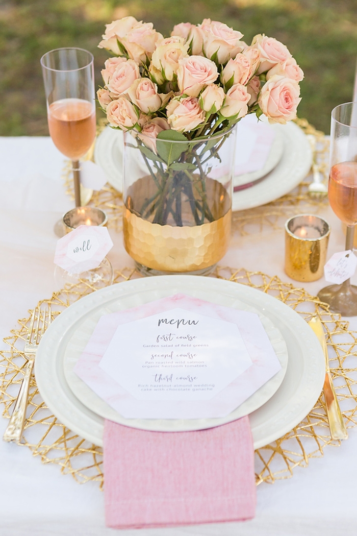 Platzkarte auf weißem Teller, schöner Rosenstrauß, kleine goldene Kerzenhalter