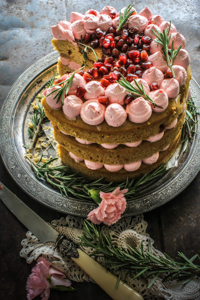 Dreistöckige Torte mit Erdbeercreme und Granatapfel, rosafarbene Nelken als Dekoration