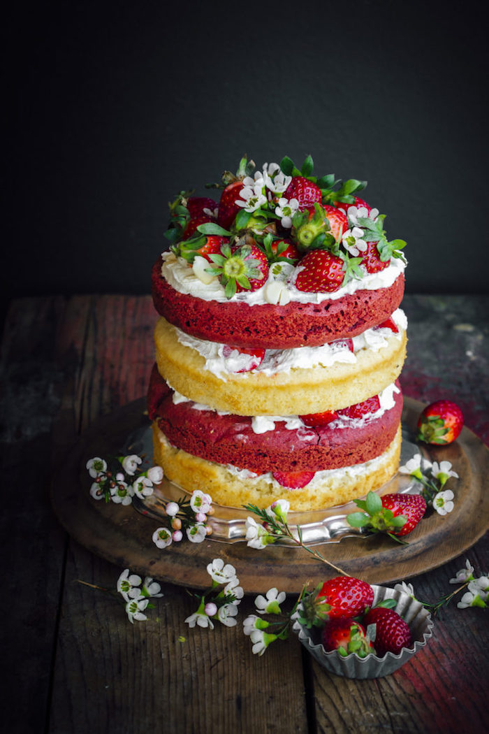 Dreistöckige Torte mit Vanillecreme und frischen Erdbeeren, dekoriert mit kleinen weißen Blüten