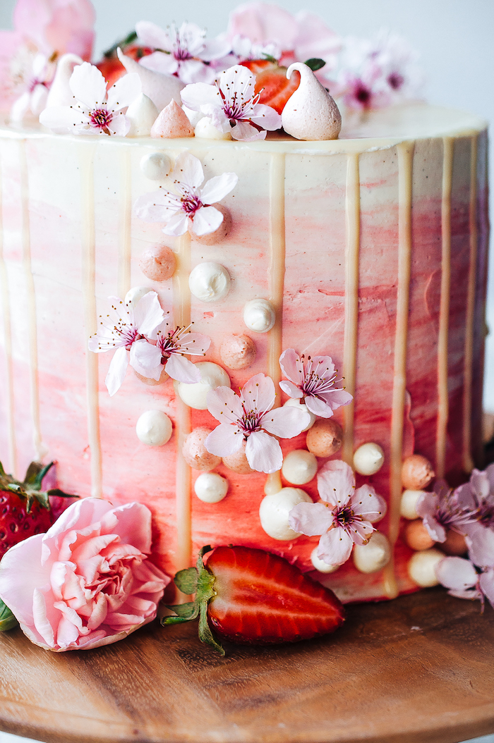 Dreistöckige Torte mit Erdbeercreme und weißer Schokolade, dekoriert mit echten Blüten und frischen Erdbeeren