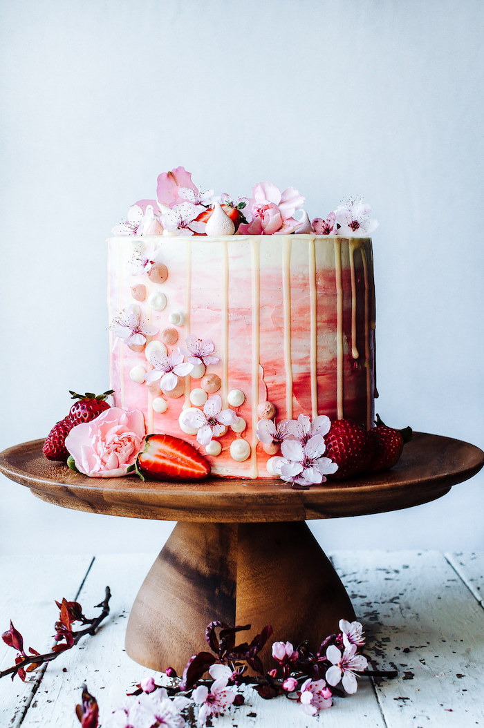 Prachtvolle selbstgemachte Hochzeitstorte mit weißer Schokolade, dekoriert mit echten Blüten und frischen Erdbeeren