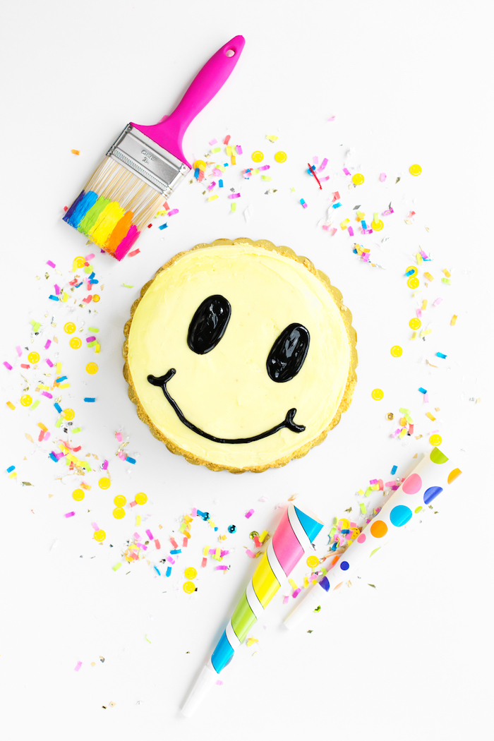 Smiley Torte selber backen und dekorieren, mit gelber Creme, Pinsel und Konfetti