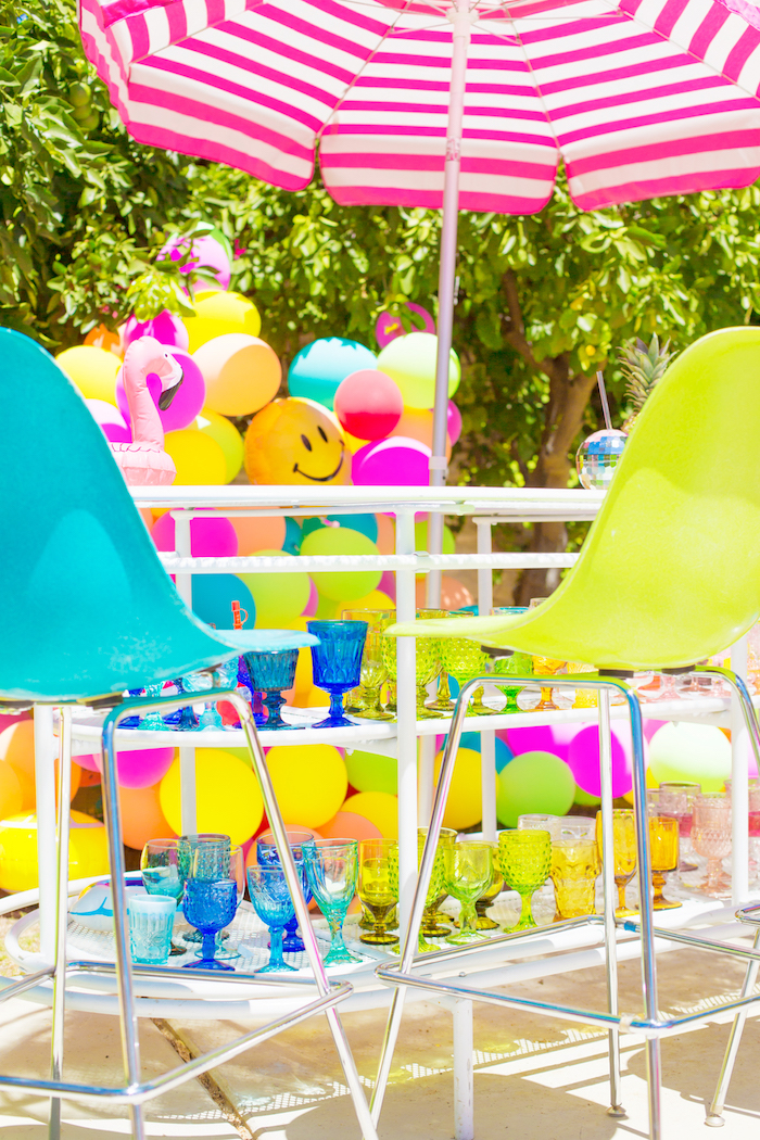 Poolparty zum Geburtstag organisieren, bunte Ballons und Gläser, gestreifter Sonnenschirm