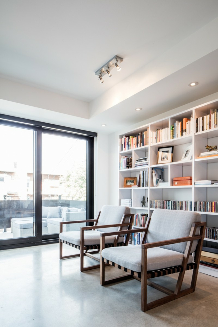 Würfel Regalsystem mit Bücher, zwei Sessel, Deckenleuchten, Betonboden Wohnbereich