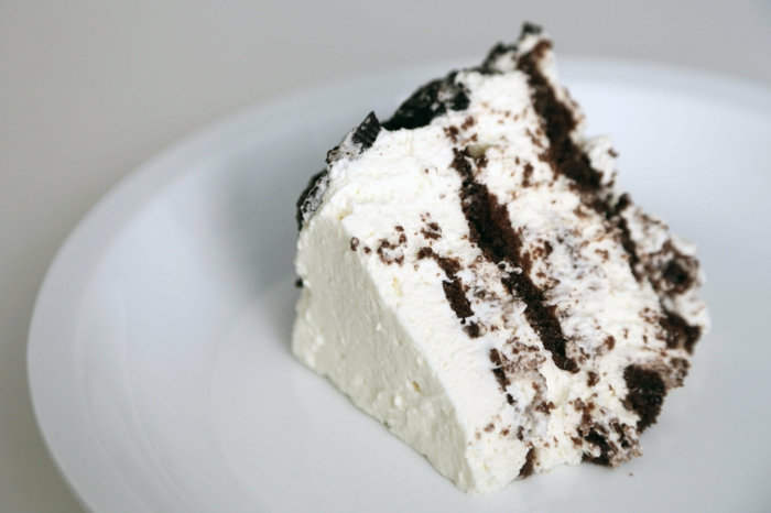weiße Torte mit Schokoladenböden in einem weißen Teller, leckere Kuchen zum Genießen