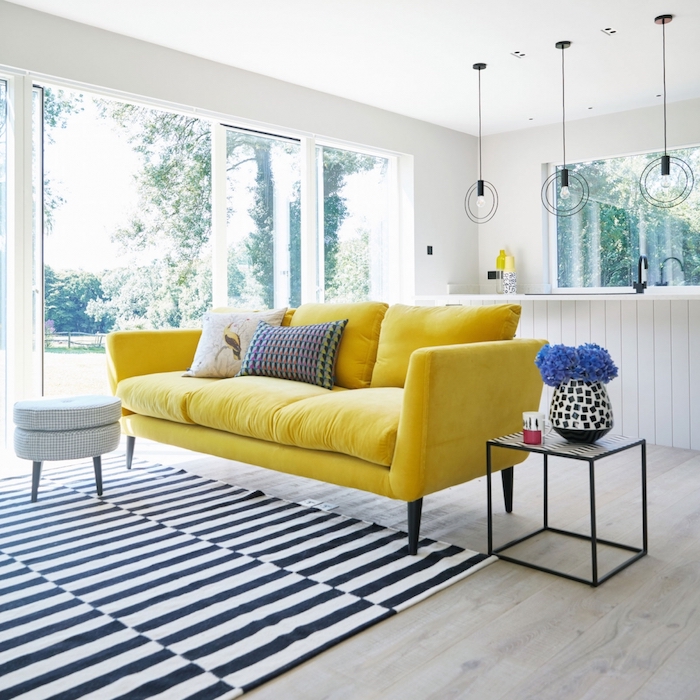 wohnzimmer wandfarbe, gelbes sofa, gestreifter teppich, runde hängelampen, blaue blumen