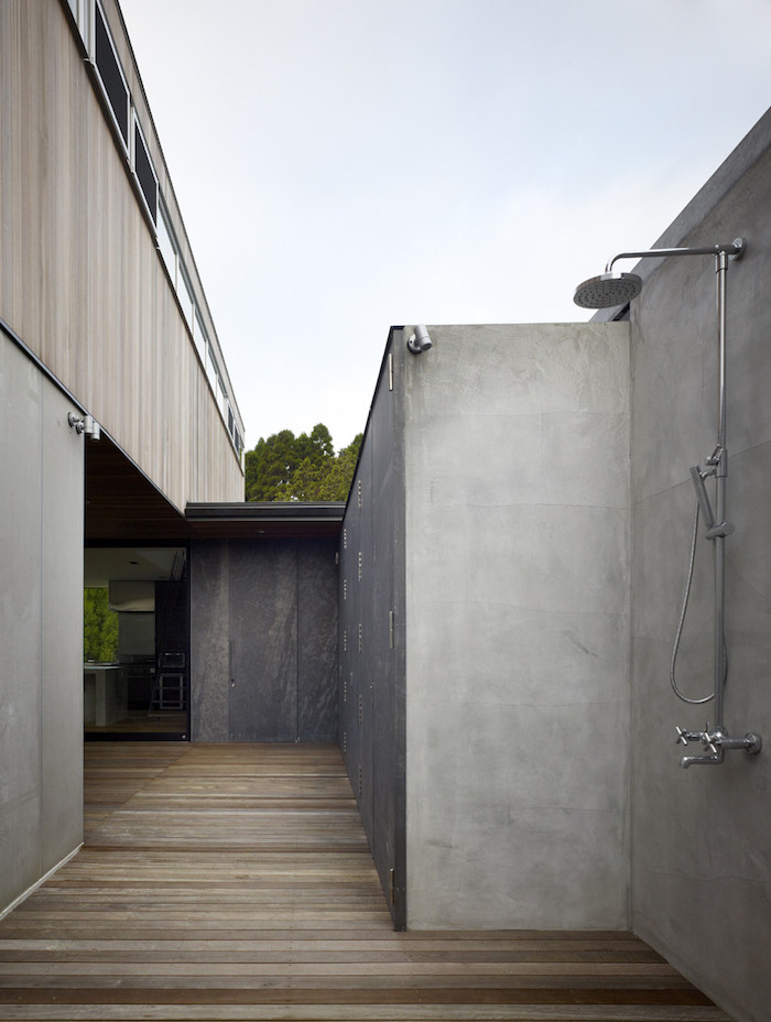 gartengestaltung ideen diy, ein haus mit einer grauen terrasse mit braunem boden aus holz und einem grauen sichtschutz, eine gartendusche edelstahl