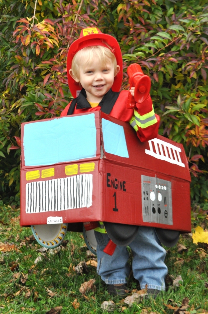 ein kleiner Feuerwehrmann mit seinem Feuerwehrwagen aus Karton, Hut von Feuerwehrmann