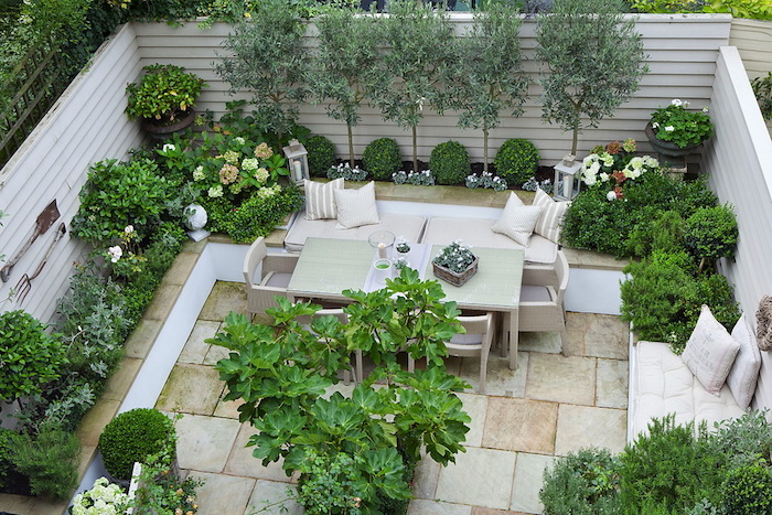 sichtschutz balkon ideen, eine terrasse mit weißen holzzaun sichtschutz und grünen bäumen und pflanzen, tisch und weiße stühle und sofas mit kissen