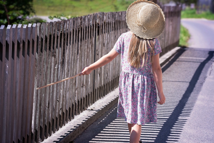 ein Mädchen spielt mit dem Zaun