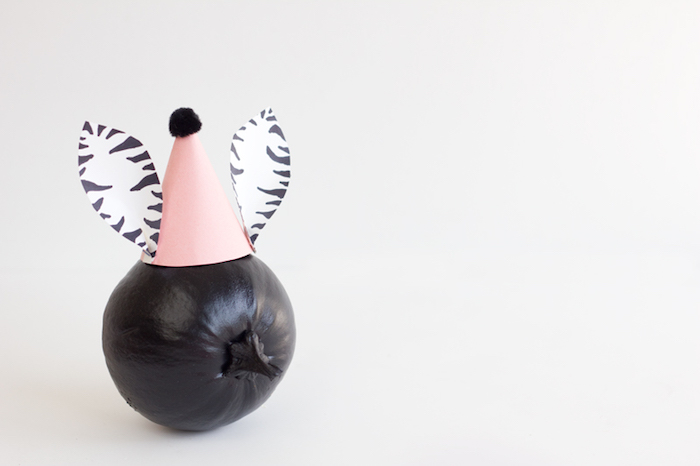 Kürbis mit schwarzer Acrylfarbe bemalen, Partyhütchen mit Ohren aus Papier basteln 