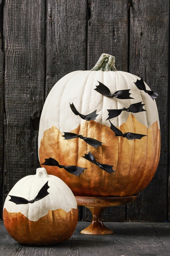 Halloween Kürbis kreativ bemalen und dekorieren, mit weißer und goldener Farbe, schwarze Schleifen als Fledermäuse