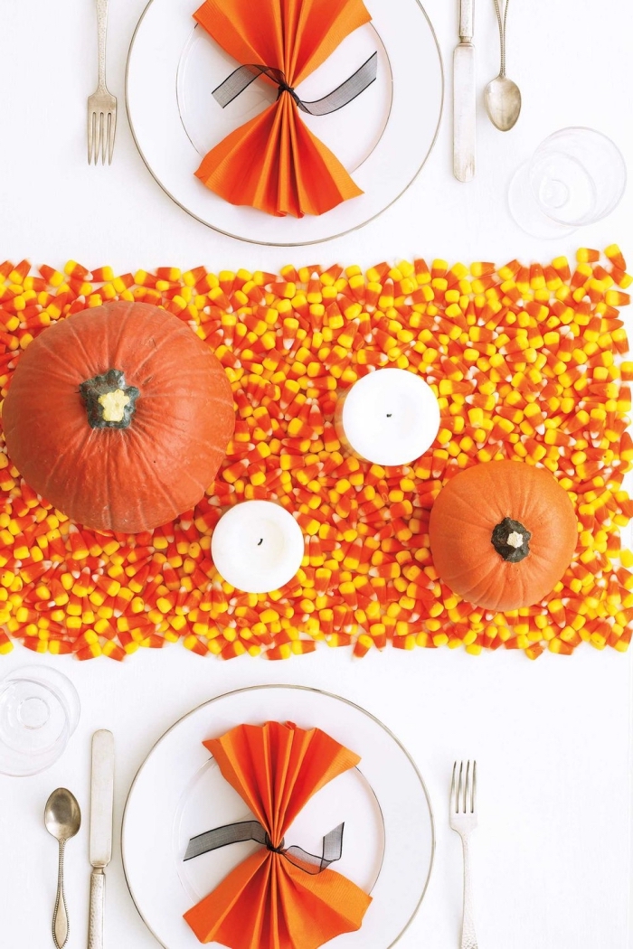 halloween ideen, tischdeko selber machen, tischläuder aus bonbons, weiße kerzen, orangenfarbene servietten