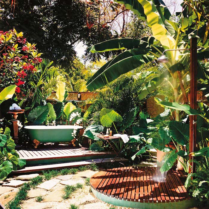 viele grüne palmen mit grünen blättern und rote blumen, ein garten mit kleiner grünen badewanne und dusche, sichtschutz für gartendusche aus exotischen pflanzen