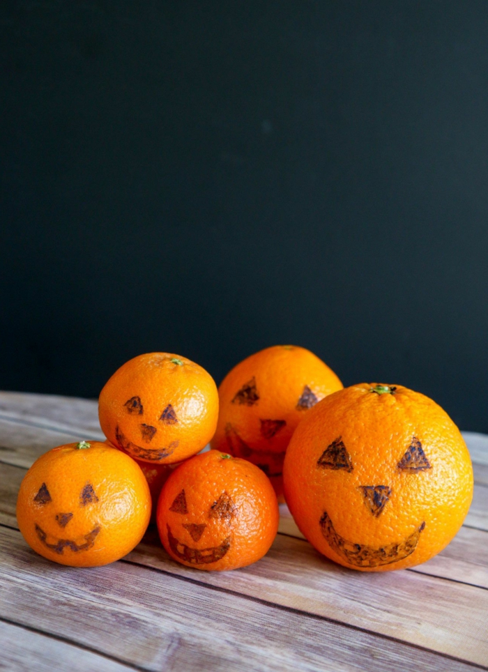 Mandarinen mit gruseligen Gesichtern, stellen Kürbisse dar, gesundes Halloween Menü