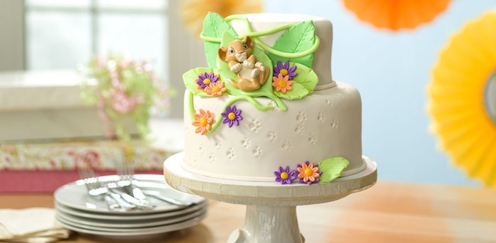 Lion King Motivtorte, Simba Figur aus Fondant, Blätter und bunte Blumen, zweistöckige Torte mit Vanillecreme