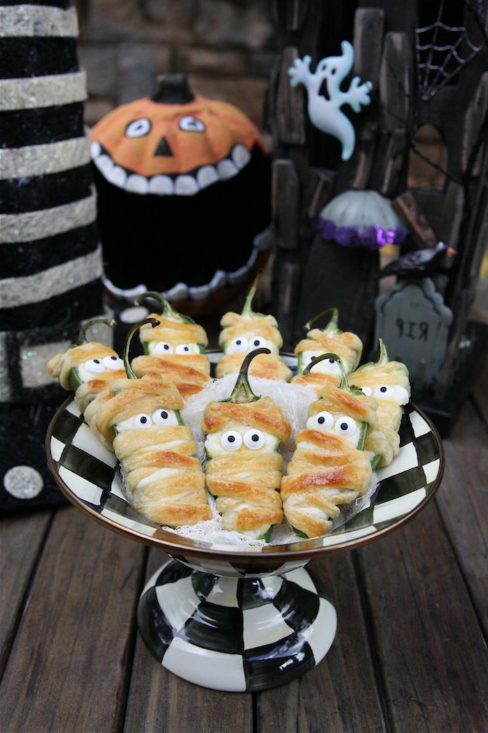 Paprikas mit Hülle aus Teig, mit weißen Augen, stellen gruselige Mumien dar, Halloween Snack Ideen