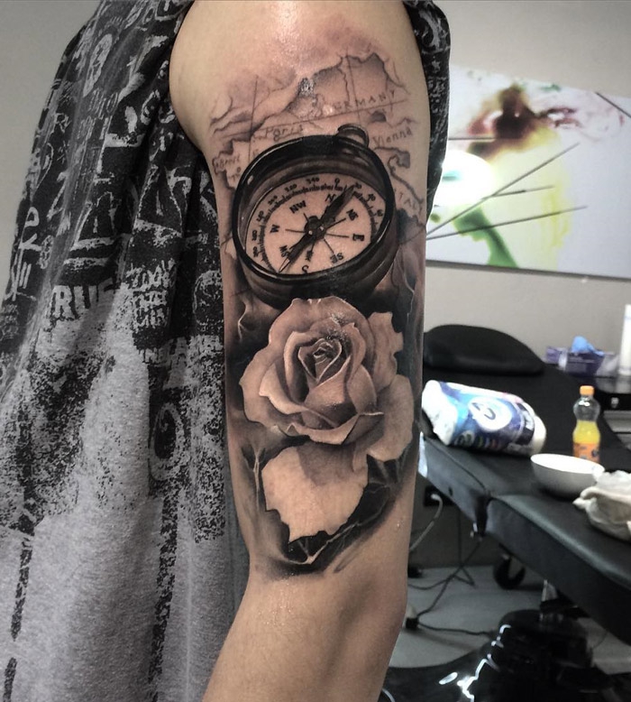 tattoo 3d am oberarm, weiße rose in kombination mit weltkarte und kompass, mann